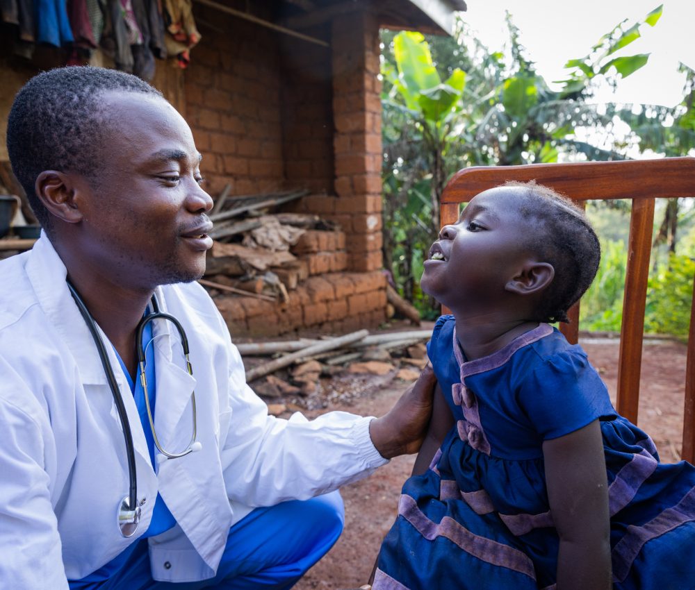 African doctor talking to a sick baby girl during a visit in a rural area in Africa